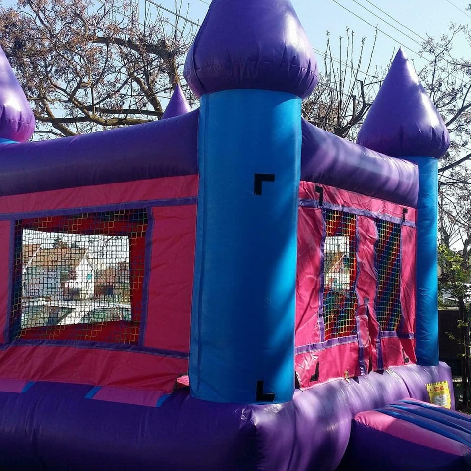 Pink and purple castle bounce house with turrets and a front step, fully inflated