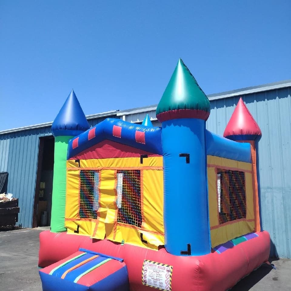 Multicoloured castle bounce house set up outdoors under a clear blue sky