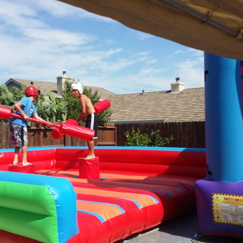 Two children playing on an inflatable game in a back yard on a sunny day
