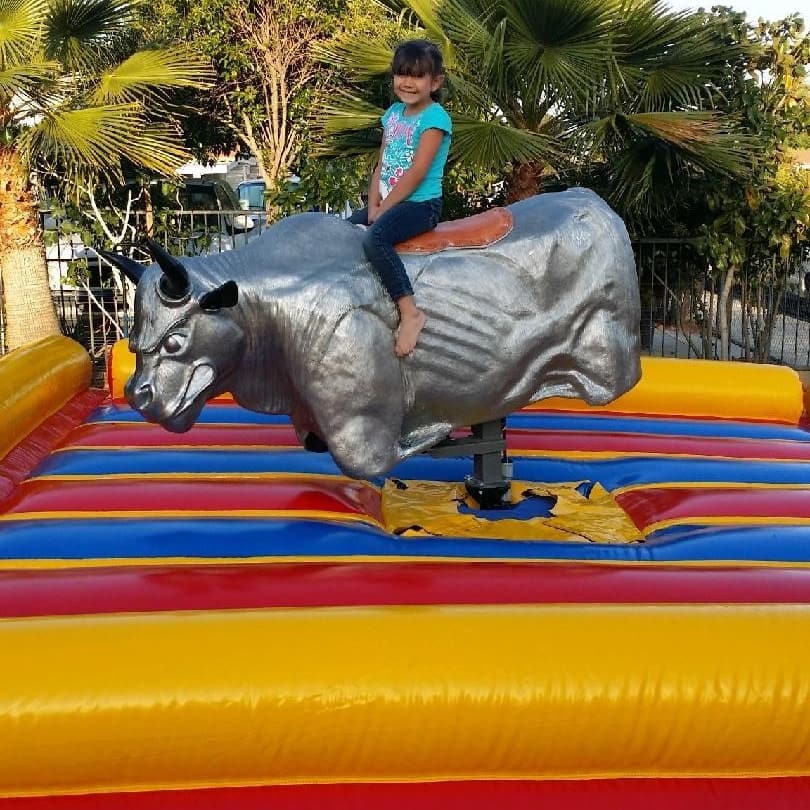 A child riding the mechanical bull on its padded inflatable base
