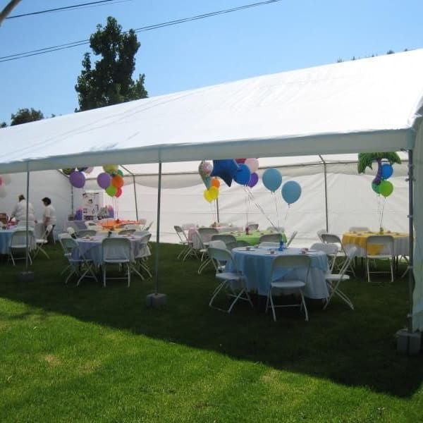 White party tent over round tables and chairs, decorated with balloons on a lawn